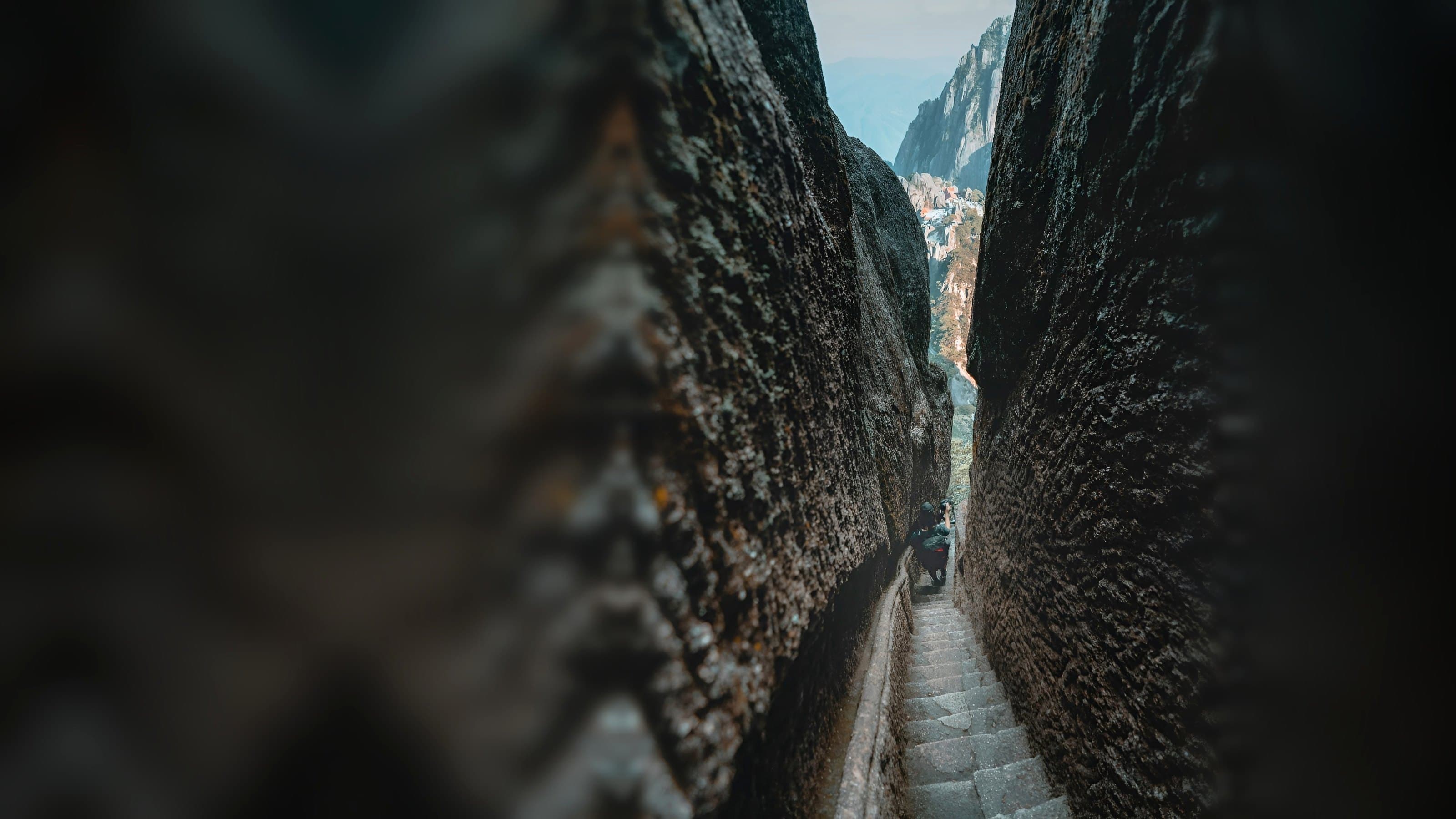 A lone traveller climbing a narrow stone stairway between granite cliffs in China’s Huangshan mountains